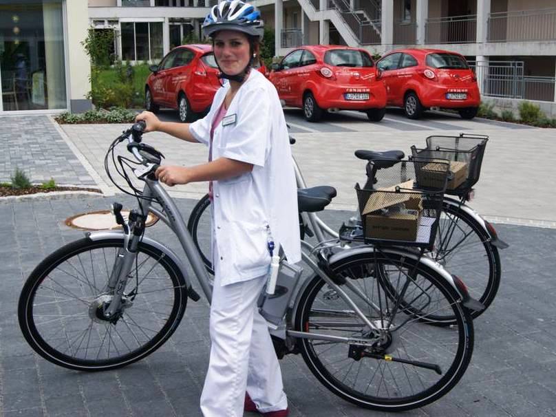Frau mit E-Bike vor E-Autos